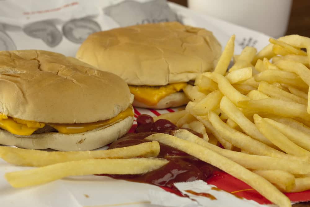 Two,cheeseburgers,and,french,fries,on,a,fast,food,bag