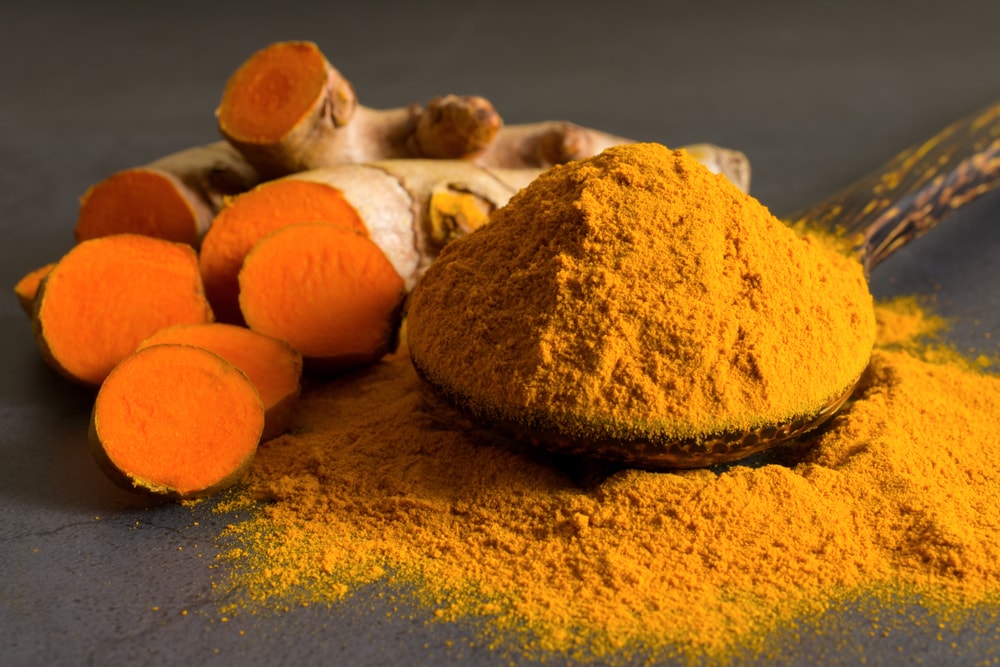 Turmeric,(curcumin),powder,in,a,wooden,ladle,and,fresh,rhizome