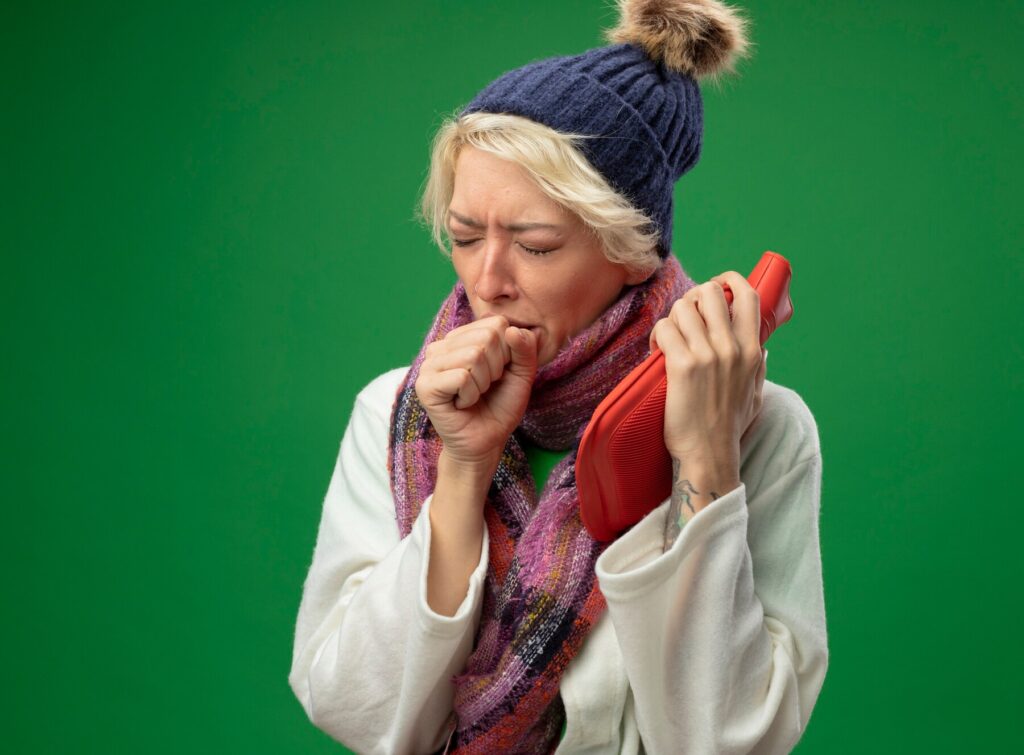 Sick Unhealthy Woman With Short Hair Warm Scarf Hat Feeling Unwell Holding Water Bottle Kep Coughing Suffering From Flu Standing Green Wall 141793 52411